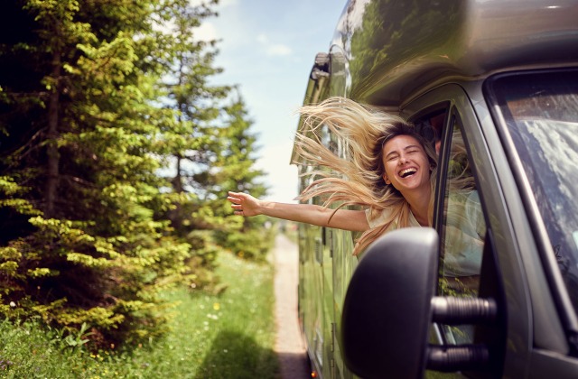Young woman leaning out the window of an RV. RV Insurance 